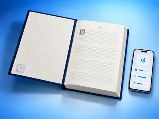 A library book with an RFID label inside its cover next to an iPhone showing the details of an NFC tag